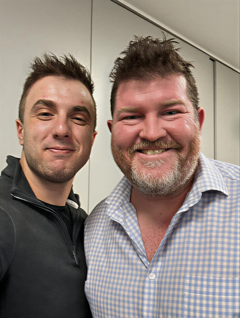 Stephan Stickley (left), and Lyndon-Jon Martin (right) take a picture together. Both are smiling at the camera. 